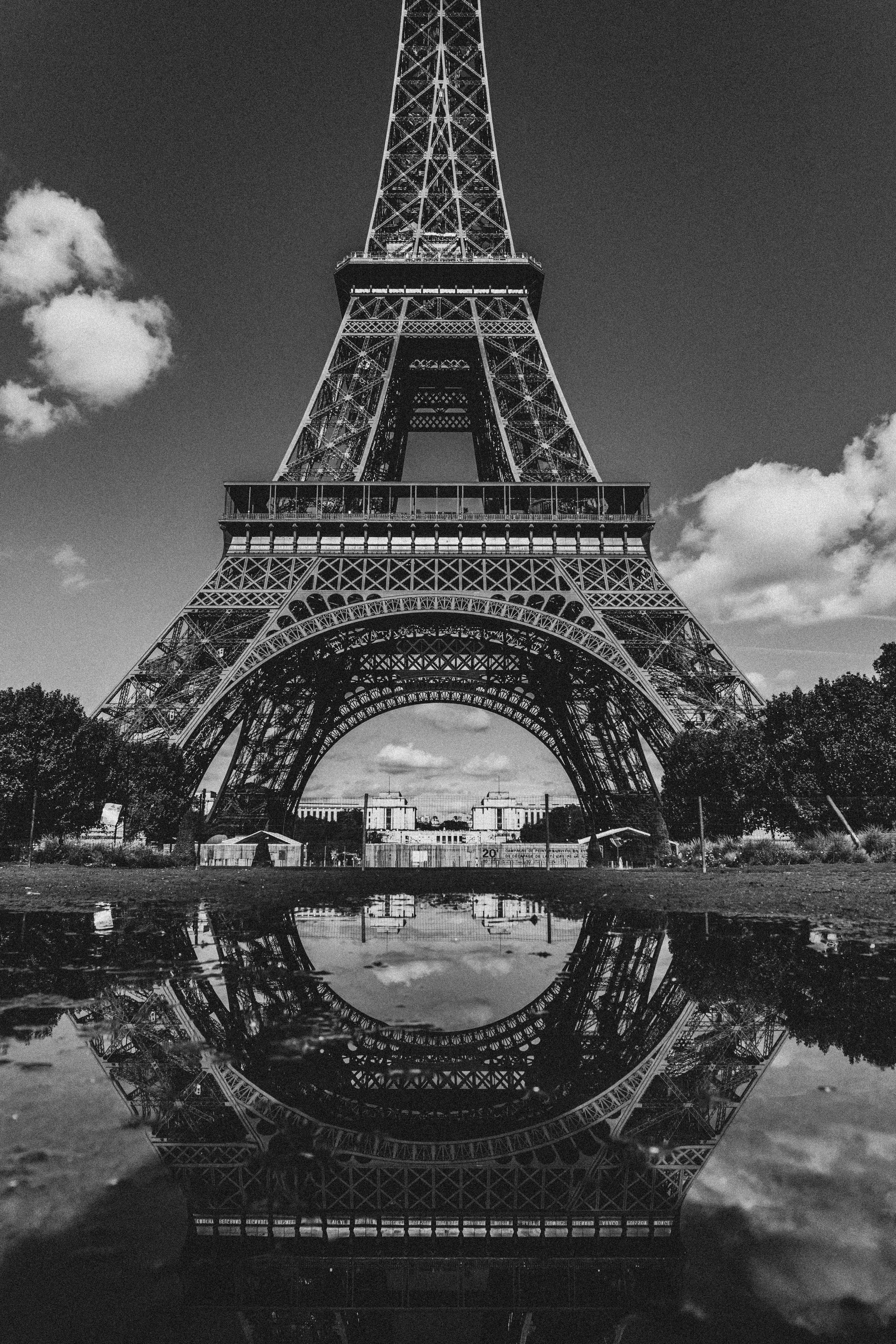 Black and white photograph of the Eiffel Tower reflected in a puddle